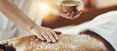 Hand streut Meersalz auf den Rücken während einer Spa-Massage, achtsame Berührung und tiefe Entspannung I WUNDERORTE