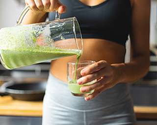 Frau gießt grünen Smoothie in ein Glas – Symbol für Gesundheit, Fitness und bewusste Ernährung I WUNDERORTE