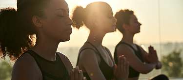  Drei Frauen meditieren im Yoga-Retreat eines Vitalhotels, Fokus auf Gesundheit und innere Balance I WUNDERORTE