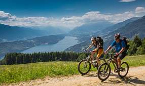 Zwei Mountainbiker auf einer Panoramatour über dem Gardasee, umgeben von Bergen, Wäldern und Fernblick – ideal für sportlichen Aktivurlaub in Norditalien I WUNDERORTE