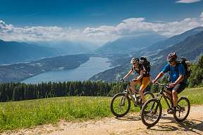Zwei Mountainbiker auf einer Panoramatour über dem Gardasee, umgeben von Bergen, Wäldern und Fernblick – ideal für sportlichen Aktivurlaub in Norditalien I WUNDERORTE