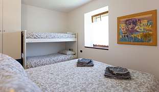 Helles, gemütliches Schlafzimmer mit Doppelbett und Etagenbett unter dem Fenster in einem familienfreundlichen Ferien-Landhaus am Gardasee von WUNDERORTE