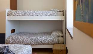 Helles Schlafzimmer mit Etagenbett, Holzfußboden und Nachttisch – perfekt für Kinder oder Reisegruppen im Ferienhaus bei Arco am Gardasee I WUNDERORTE