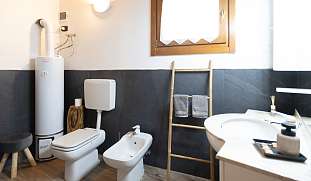 Modernes Tageslichtbad mit Bidet, WC, Waschbecken und liebevollen Holzdetails im Berghaus bei Arco am Gardasee I WUNDERORTE
