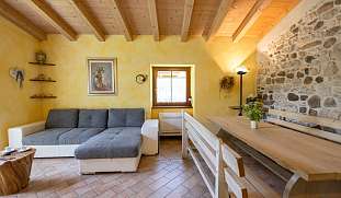 Gemütliches Wohnzimmer mit Holzbalkendecke, Natursteinwand und großer Couch und Esstisch - ideal für Familienurlaub am Gardasee von WUNDERORTE