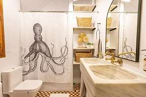 Helles Badezimmer mit Duschvorhang Oktopus  - goldene Armaturen, karierte Fußboden-Fließen in braun und beige