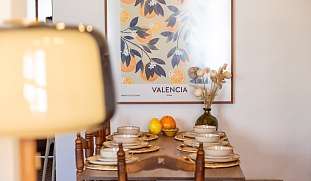 Essbereich mit gedecktem Holztisch und Naturmaterialien mit Kunstdruck an der Wand