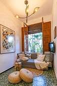 Lounge-Ecke mit gemütlichem Sofa, Poufs, Kunst und offenem Fenster mit braunem Rahmen am Ende des Flurs zum Träumen von WUNDERORTE