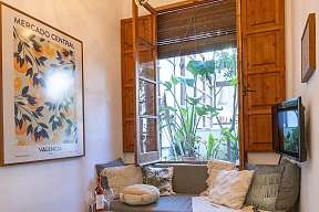 Lounge-Ecke mit gemütlichem Sofa, Poufs, Kunst und offenem Fenster mit braunem Rahmen am Ende des Flurs zum Träumen von WUNDERORTE