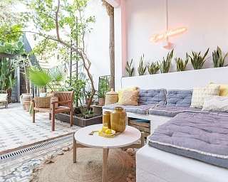 Blick auf Lounge im Innenhof des Ferienhaus mit hellblauen Kissen - stilvoll abgestimmte Farben der Dekoration, Fliesen und Pflanzen zum Wohlfühlen