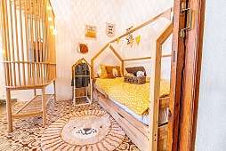 Verspieltes Kinderzimmer mit Gitterbett, Hausbett und Tierteppich - ideal für Familienurlaub am Mittelmeer I WUNDERORTE
