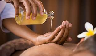 Warmes Öl fließt in an Hand auf dem Rücken für eine Ayurveda Behandlung Symbol für Ruhe, Verwöhnung, Genuss tiefer Erholung