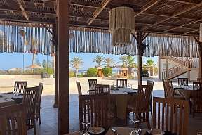 Überdachte Restaurantterrasse mit Palmenblick am Strand des Breakers Hotels – entspannter Genussurlaub am Roten Meer
