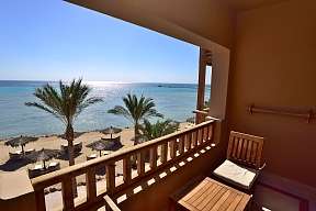 Blick vom Balkon über Palmen und Sandstrand auf das Rote Meer – mit frischem Obst und Holzmöbeln am Hotel The Breakers in Ägypten