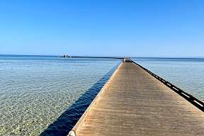 Langer Holzsteg führt über flaches Wasser ins Meer – Blick auf das Rote Meer vom The Breakers