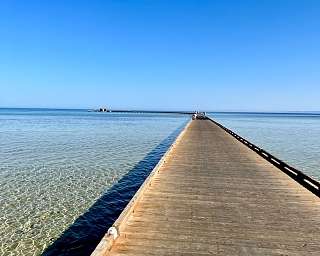 Langer Holzsteg führt über kristallklares Wasser ins offene Meer – Symbol für Klarheit, Weite und mentale Ruhe. Retreat-Erlebnis mit WUNDERORTE am Roten Meer.
