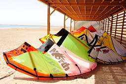 Kites unter Holzüberdachung am Strand in Soma Bay – bunte Ausrüstung für Kitesurfurlaub in Ägypten