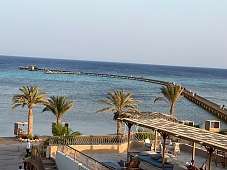 Blick über Palmen, Strand und Jetty auf das türkisblaue Rote Meer am Hotel The Breakers in Soma Bay