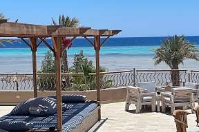 Sonnenterrasse mit Tischen und Blick auf das türkisblaue Meer am Hotel The Breakers in Ägypten
