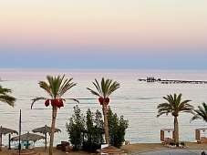 Blick vom Strandhotel auf Palmen, Himmel in Pastell und Holzsteg am Roten Meer – The Breakers