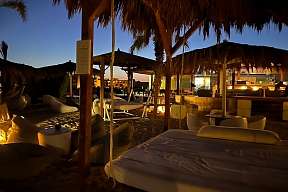 Gemütlich beleuchtete Beachbar mit Loungemöbeln und Strohdächern – Abendstimmung direkt am Strand in Soma Bay