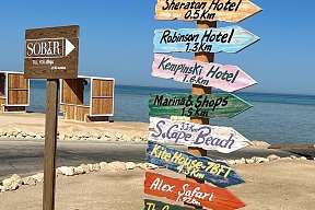 Bunter Holzwegweiser vor dem Roten Meer – Orientierung am Strand des Breakers Hotels in Soma Bay