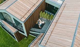 Drohnenaufnahme eines Paares auf einer geschützten Design-Terrasse im Luxus-Chalet – Ruhe, Rückzug und Zweisamkeit in Südti