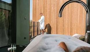 Frau entspannt in einer modernen Outdoor Badewanne mit Blick auf ihren Partner – Private Spa und Designarchitektur im Wellnesshotel in Südtirol I WUNDERORTE
