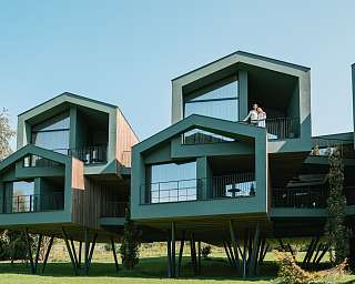 Ein Paar steht auf dem Balkon eines stilvollen Designhotels mit moderner Chalet-Architektur und Panoramablick in Südtirol – WUNDERORTE als Rückzugsort