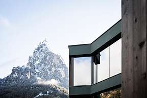Detailansicht einer modernen Designsuite mit großen Glasfronten vor schneebedecktem Dolomitengipfel – Architektur trifft Winterstille I WUNDERORTE