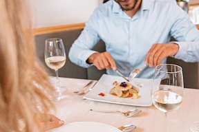 Ein Paar genießt ein stilvolles Dinner mit feiner Küche und Weißwein in einem romantischen Wellnesshotel in Tirol – kulinarische Verwöhnmomente I WUNDERORTE