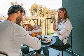 Ein Paar genießt ein entspanntes Frühstück auf der privaten Terrassensuite mit Picknickkorb und Naturblick – kulinarische Morgenruhe I WUNDERORTE