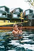 Paar im Naturpool vor modernen Chalet-Suiten – Wellness und Lebensfreude in Südtirol – WUNDERORTE