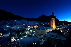 Beleuchtete Kirche und verschneite Dächer in Kastelruth bei Nacht – stimmungsvolle Winterlandschaft für einen ruhigen Adventurlaub in Südtirol I WUNDERORTE