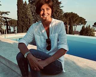 Porträt Frau mit weißer, lockere Bluse und Jeans am Pool sitzend  - warm-ruhe und natürlich 