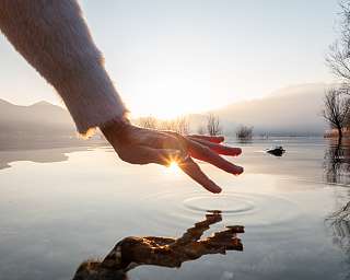 Hand als Symbol für bewusstes Sehen und Fühlen I WUNDERORTE I ALT: Hand als Symbol für Sehen und Fühlen spiegelt sich in den Sonnenstrahlen im Wasser I WUNDERORTE