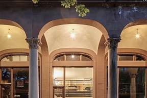 Beleuchtetes Designloft in Meran mit hohen Fenstern und stilvollem Innenraum am Abend I WUNDERORTE
