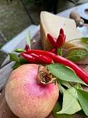 Frischer Granatapfel mit roten Chilis und Käse auf einem Holztisch im Garten – mediterraner Genussmoment I WUNDERORTE