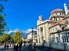 Historisches Kurhaus Meran an der Promenade mit Alpenblick und Spaziergängern bei Sonnenschein I WUNDERORTE