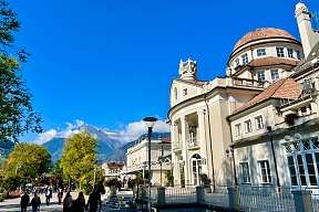 Historisches Kurhaus Meran an der Promenade mit Alpenblick und Spaziergängern bei Sonnenschein I WUNDERORTE