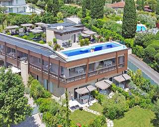 Drohnenaufnahme des modernen LAMASU-Designresorts am Gardasee mit Rooftop-Infinitypool, Sonnendeck und grüner Parkanlage – ein exklusiver WUNDERORT für achtsamen Rückzug.