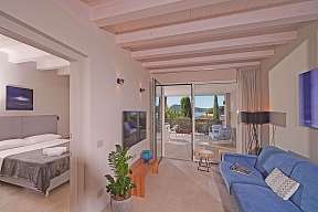 Offener Wohn- und Schlafbereich der Lamasu-Ferienwohnung am Gardasee mit blauem Sofa, Doppelbett, TV und Zugang zur möblierten Terrasse I WUNDERORTE