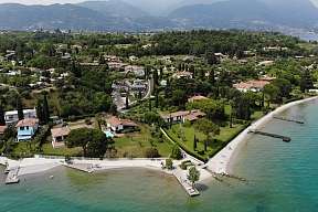 Drohnenaufnahme des Lamasù Resorts mit eigenem Strand, Zypressen und türkisblauer Gardasee-Bucht I WUNDERORTE