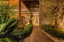 Eingangsweg des WUNDERORT Lamasu Wellness-Resorts am Gardasee, warm beleuchtet zwischen Olivenbaum und Palmen
