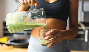 Sportliche Frau macht eine Detox Kur und trinkt einen frisch gepressten grünen Saft.