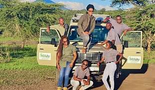 Das Team von nature responsible Safari freut sich auf neue Gäste und sitzen mit den Gründerinnen vor einem Safari Jeep in Tansania.