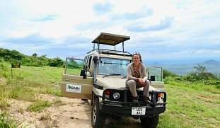 Martina von responsible Safari sitzt entspannt auf einem Safari-Jeepinmitten der Natur mit Blick in die Weite
