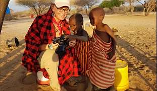 Köchin des Safari Teams zeigt Massai Kindern ihre Kamera – alle lachen herzlich. Symbol für Freundschaft, Freuden Interesse  in Afrika 