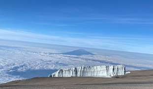 Blick auf den Gletscher am Kilimandscharo mit weiter Wolkendecke und Mount Meru  am Horizont in Tansania