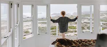 Frau blickt vom Balkon aufs Meer, Natur und Weite I WUNDERORTE
